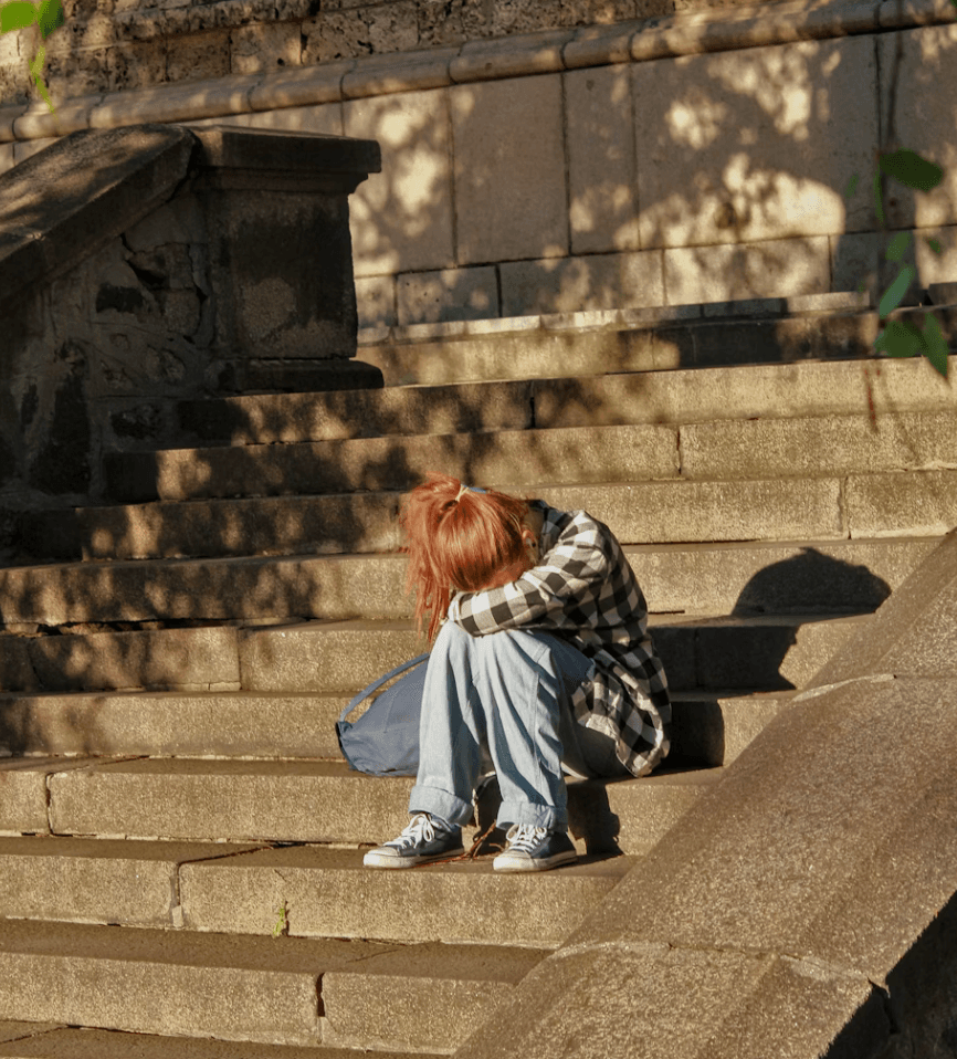 Child sitting alone at school after experiencing bullying from classmates, appearing sad and withdrawn